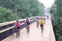 People Biking Over Bridge on the Musketawa Trail